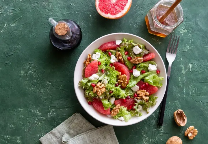 Insalata con pompelmo, noci e formaggi magri quali sono, condita con miele e aceto balsamico.