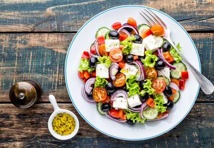 Insalata greca con feta, pomodorini, olive, cetrioli e cipolla rossa. Perfetta per una dieta leggera e gustosa.