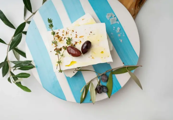 Blocchi di feta conditi con erbe e olive, pronti per essere gustati. Un'ispirazione su come fare la feta in casa.