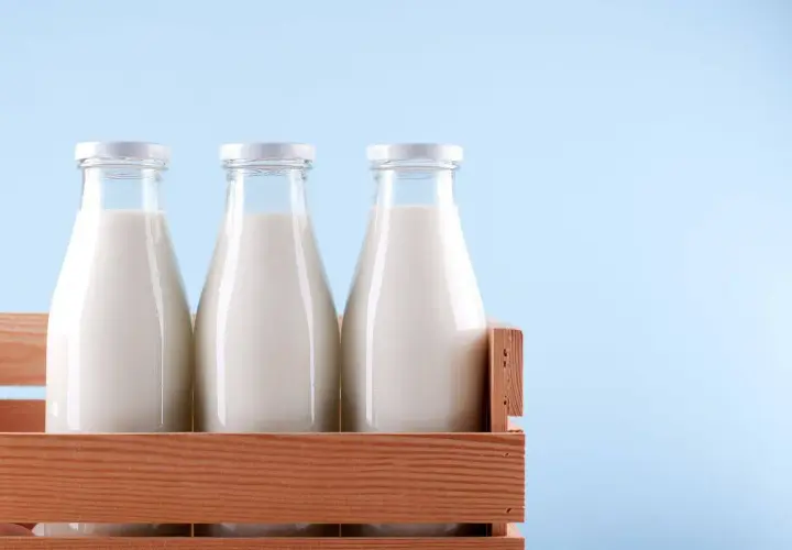 Tre bottiglie di latte fresco in una cassa di legno, pronte per essere pastorizzate.