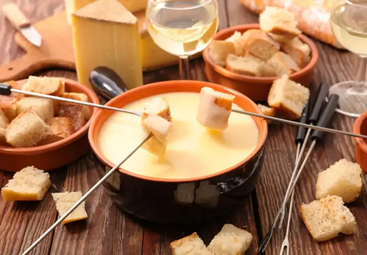 Fonduta cremosa con pane croccante e formaggio svizzero. Gli ingredienti perfetti per una serata conviviale.