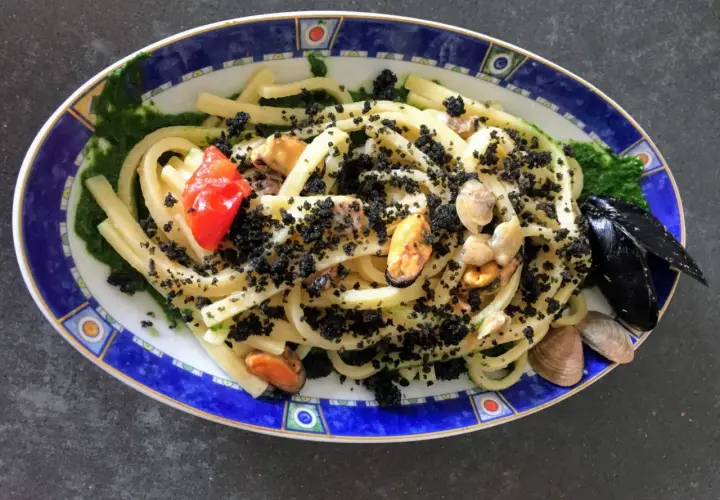 Scialatielli con cozze, pomodorini e una spolverata di pecorino grattugiato, su un letto di salsa verde.
