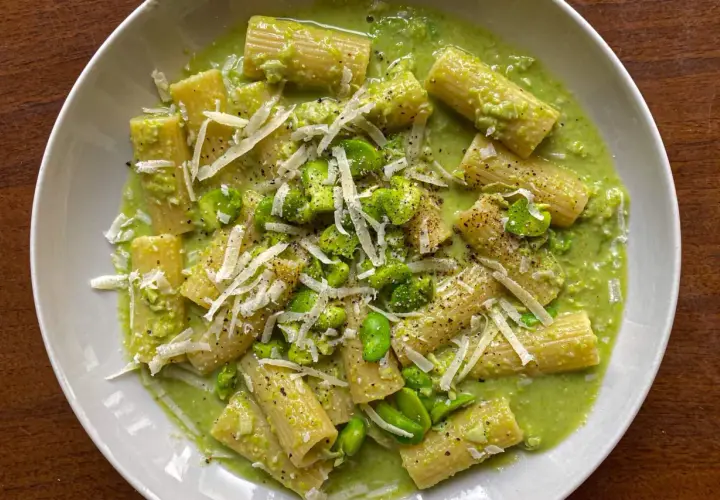 Piatto di pasta con fave fresche, crema verde e scaglie di pecorino. Un primo piatto primaverile invitante.