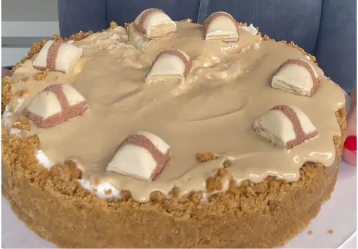 Cheesecake con copertura cremosa e pezzi di Kinder Bueno, un dolce irresistibile per gli amanti del cioccolato.