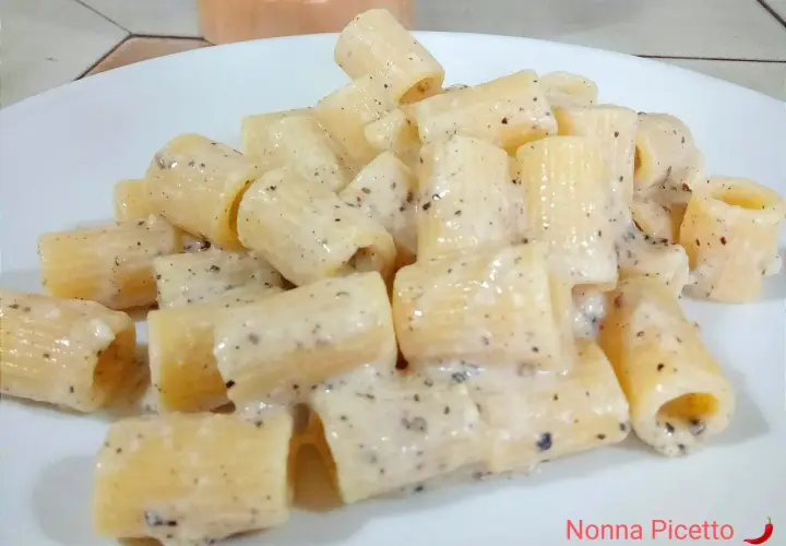 Un piatto di pasta cacio e pepe, con rigatoni cremosi e pepe nero macinato.