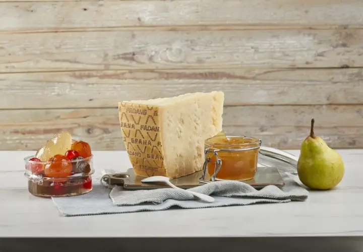 Un pezzo di Grana Padano stagionato, un vasetto di miele dorato e frutta candita, pronti per un abbinamento delizioso.
