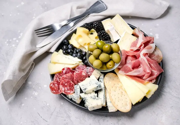 Bei taglieri con salumi, formaggi misti, olive verdi, frutti di bosco e cracker.