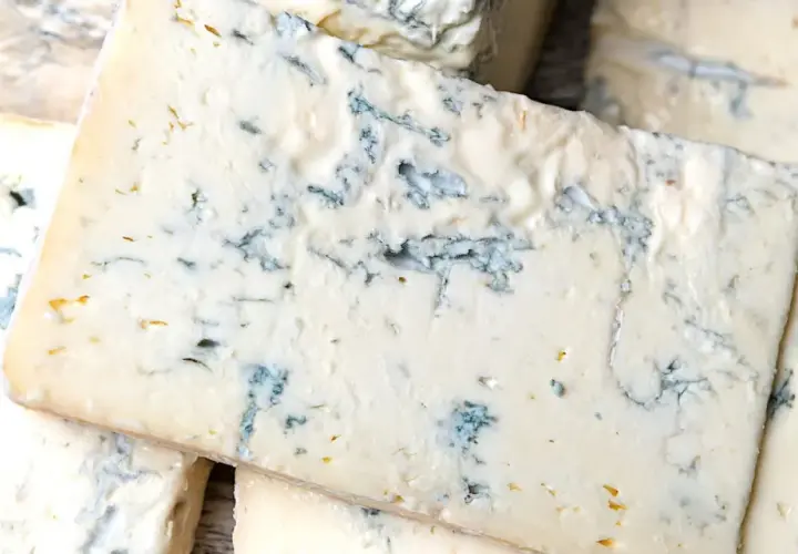 Fette di formaggio verde, con venature blu intenso, che ricordano il sapore deciso del gorgonzola.