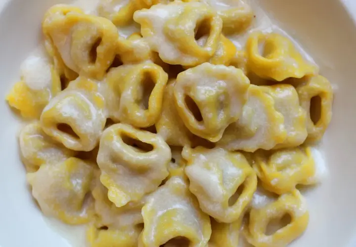 Tortellini freschi immersi in una cremosa fonduta di parmigiano, un abbraccio di sapore.