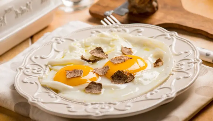 Uova al tegamino con scaglie di tartufo nero, un'idea per ricette semplici e raffinate.