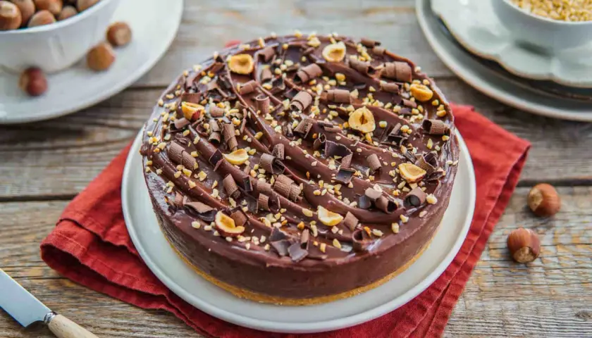 Delizioso cheesecake alla nutella, ricoperto di riccioli di cioccolato e nocciole tostate.