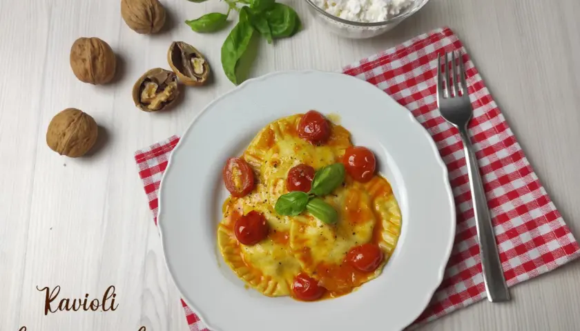 Ravioli ripieni di formaggio fresco e noci, conditi con pomodorini e basilico. Una deliziosa ricetta da provare!