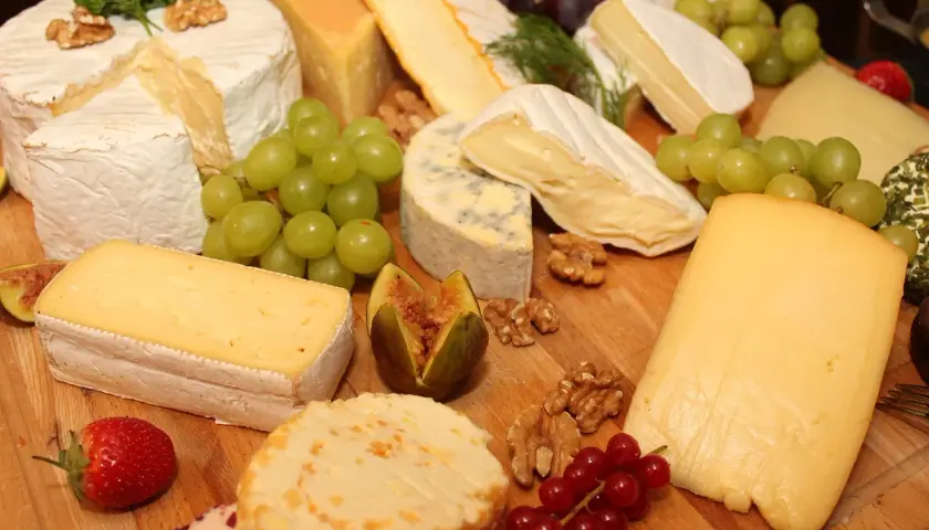 Un ricco assortimento di formaggi tipi, con uva, fichi, noci e fragole, perfetto per un aperitivo gourmet.