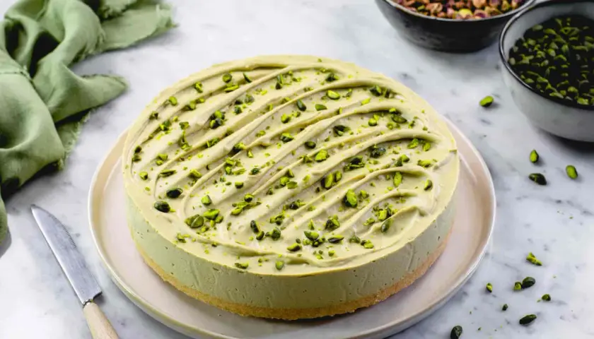 Delizioso cheesecake al pistacchio, guarnito con granella verde brillante. Un tripudio di gusto e colore.