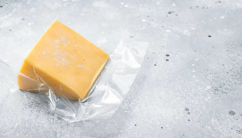 Un pezzo di formaggio giallo, sottovuoto, pronto per essere conservato. Quanto dura il formaggio sottovuoto?