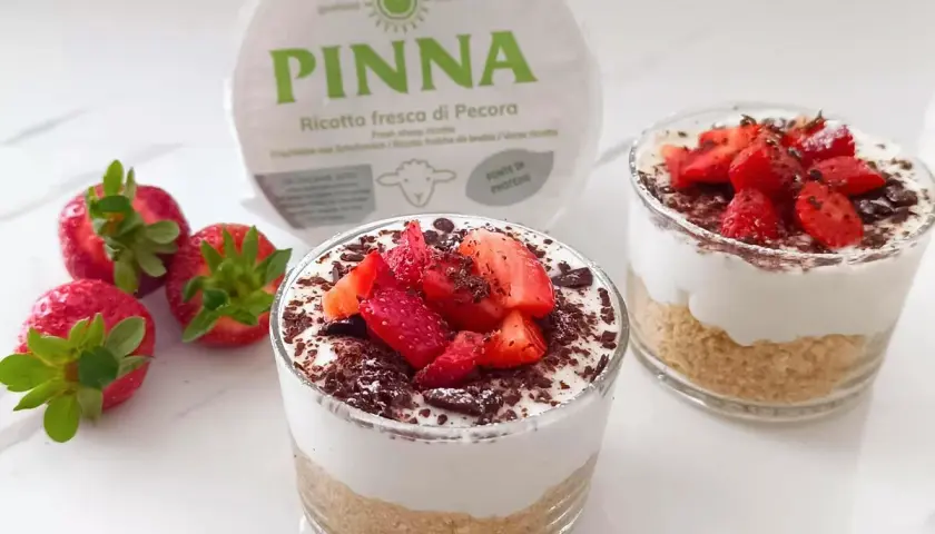 Delizioso dolce al bicchiere con ricotta fresca, fragole e scaglie di cioccolato. Perfetto per un dessert leggero e gustoso.