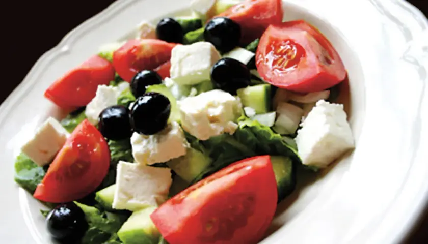 Insalata greca con pomodori, cetrioli, olive nere e cubetti di formaggio feta.