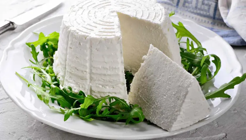 Formaggio fresco su un piatto bianco con rucola, ideale per chi cerca alimenti senza caseina.