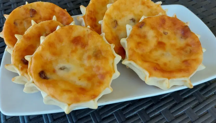 Sei formaggelle di formaggio dorate e invitanti, disposte su un piatto bianco.