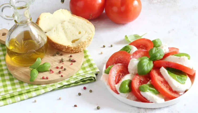 Un'incredibile insalata caprese, con pomodori freschi, mozzarella e basilico, pronta per essere condita con olio d'oliva.