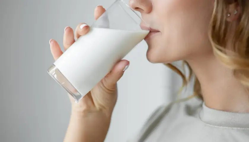 Donna bionda beve un bicchiere di latte. C'è chi dice che il latte fa ingrassare, ma lei sembra goderselo.