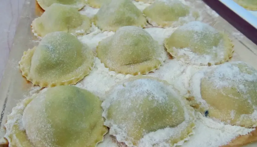 Ravioli verdi su vassoio, perfetti con cosa sostituire la ricotta nella dieta.