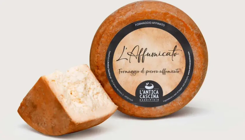 Formaggio di pecora affumicato, con una fetta tagliata. L'etichetta riporta "L'Affumicato" e "Formaggio di pecora affumicato".