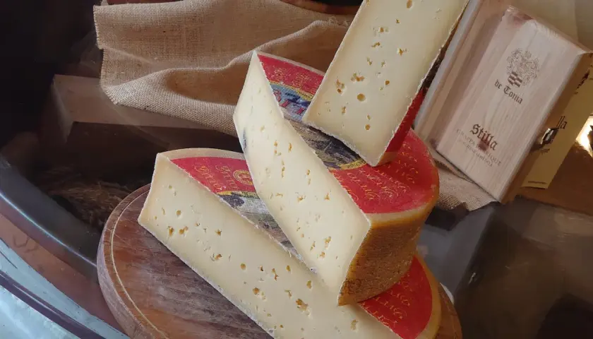 Fette di formaggio stagionato, con buchi, su un tagliere. Attenzione, la scamorza fa ingrassare!