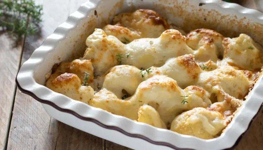 Cavolfiore al forno con pangrattato e formaggio filante, guarnito con rametti di timo fresco.