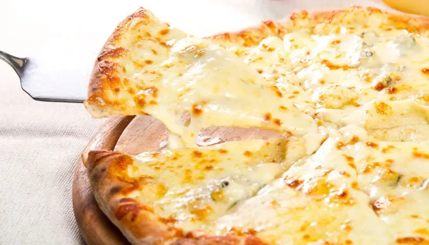 Una fetta di pizza ai 4 formaggi filante viene sollevata da una pala, mostrando la crosta dorata e il formaggio fuso.