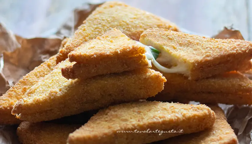 Triangoli dorati di formaggio in carrozza, con il formaggio filante che fuoriesce da uno.