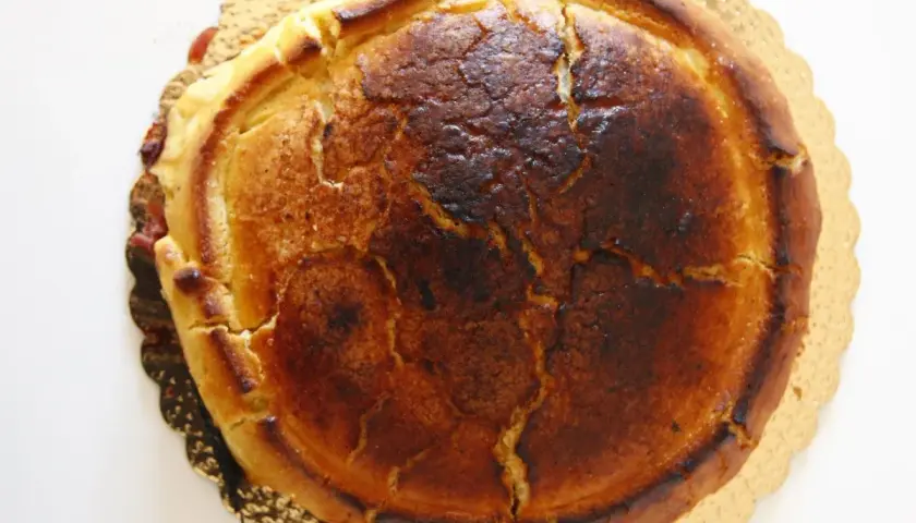 Crostata ricotta e visciole dorata, con la crosta leggermente bruciacchiata e un ripieno invitante.