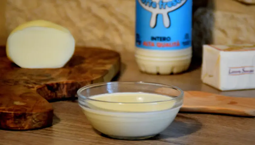 Una ciotola di cremosa fonduta di scamorza affumicata, con latte fresco e burro, pronta per essere gustata.