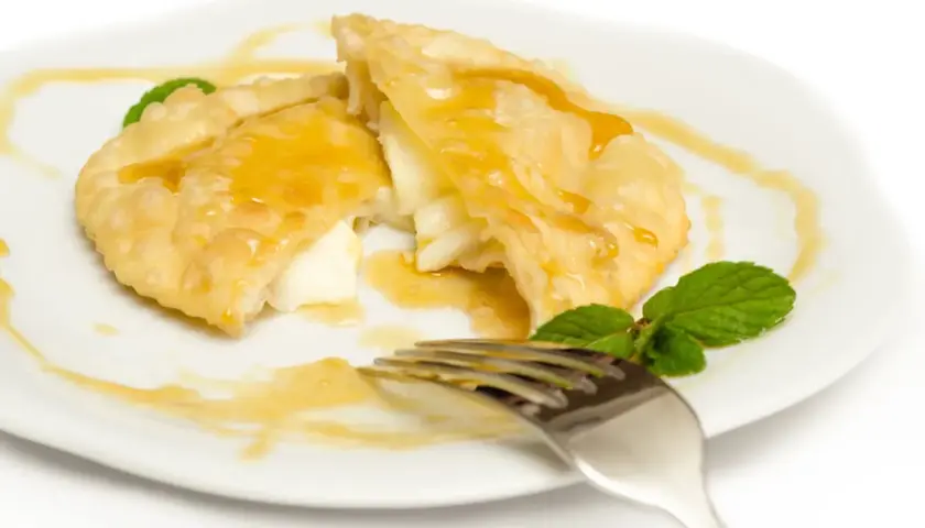 Seadas al miele, un dolce fritto ripieno di formaggio, irrorato di miele dorato e guarnito con menta fresca.