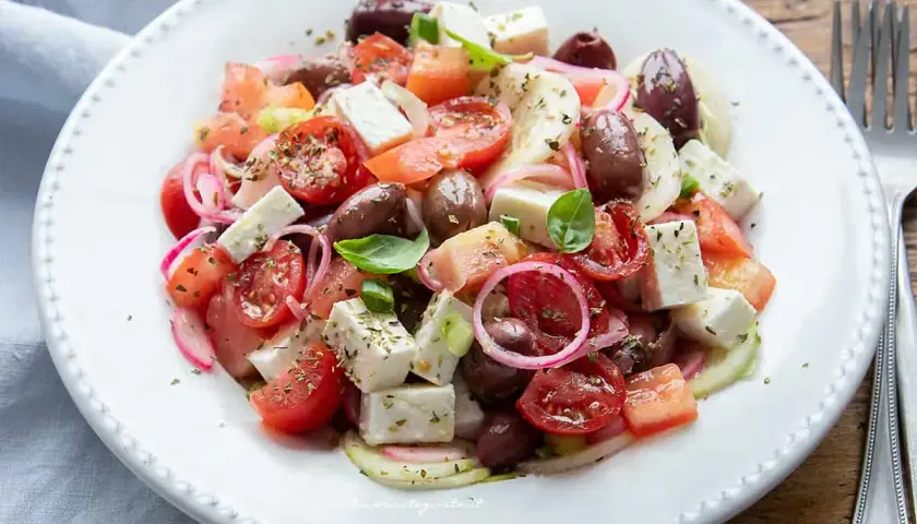 Insalata fresca con pomodorini, olive, cipolla rossa e cubetti di feta, condita con erbe aromatiche.