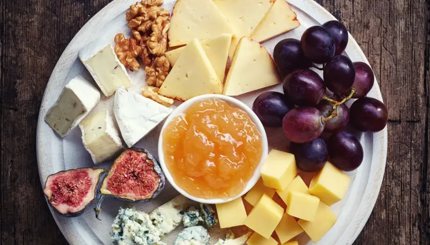 Vassoio con formaggi misti, uva, fichi, noci e una ciotola di composta di pere per formaggi.