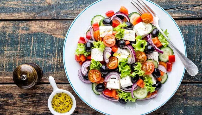 Insalata greca con feta, pomodorini, olive, cetrioli e cipolla rossa. Perfetta per una dieta leggera e gustosa.