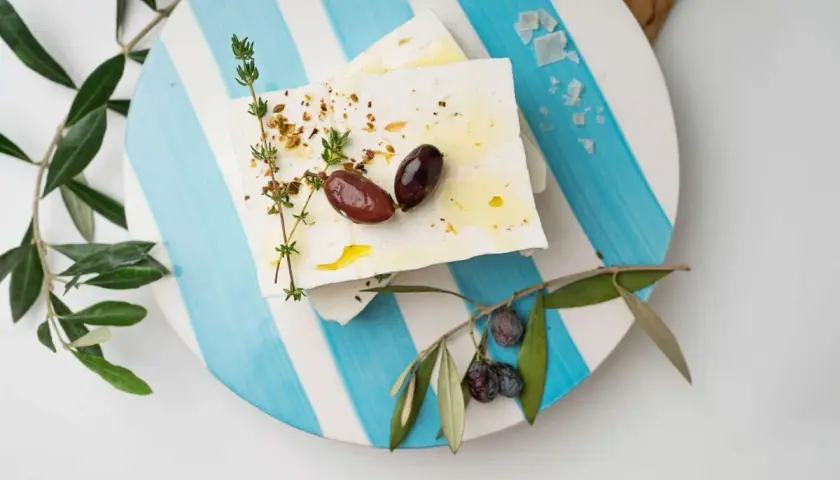Blocchi di feta conditi con erbe e olive, pronti per essere gustati. Un'ispirazione su come fare la feta in casa.