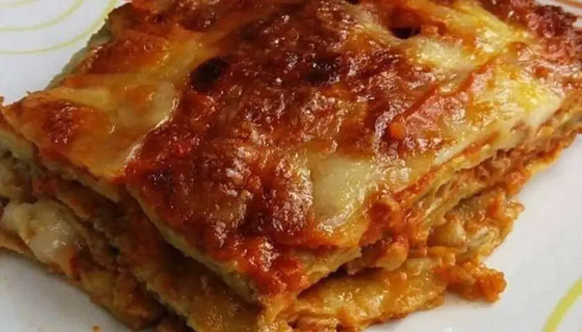 Una fetta di melanzane alla parmigiana, stratificata e dorata, con formaggio filante e sugo rosso.