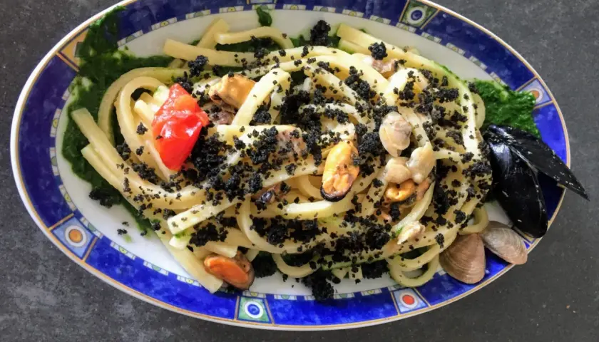 Scialatielli con cozze, pomodorini e una spolverata di pecorino grattugiato, su un letto di salsa verde.