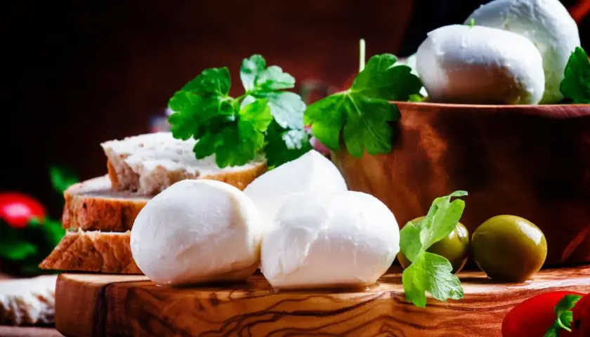 Mozzarelle fresche su tagliere di legno, con pane, olive e prezzemolo. Un'idea per un antipasto leggero, considerando le mozzarelle calorie.