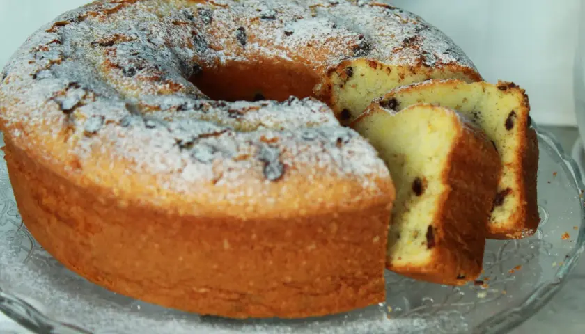 Un soffice ciambellone allo yogurt, cosparso di zucchero a velo e gocce di cioccolato, pronto per essere gustato.