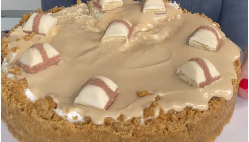 Cheesecake con copertura cremosa e pezzi di Kinder Bueno, un dolce irresistibile per gli amanti del cioccolato.