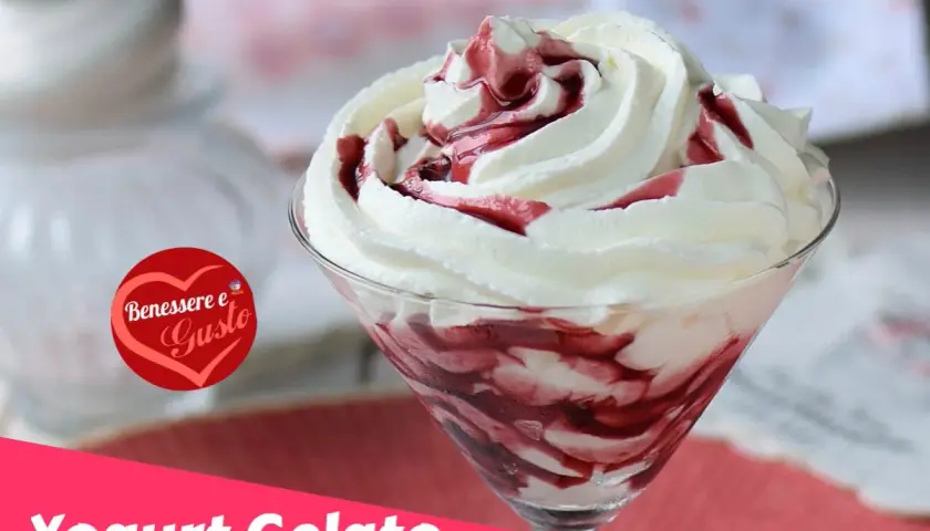 Coppa di gelato con yogurt greco e variegatura ai frutti di bosco, guarnita con panna montata.