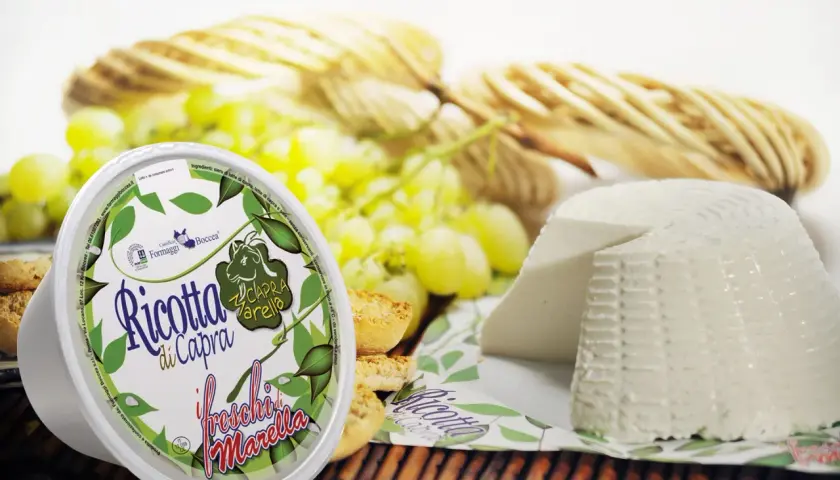Formaggi di capra: ricotta fresca e un formaggio a forma di cono, accompagnati da uva e crostini.