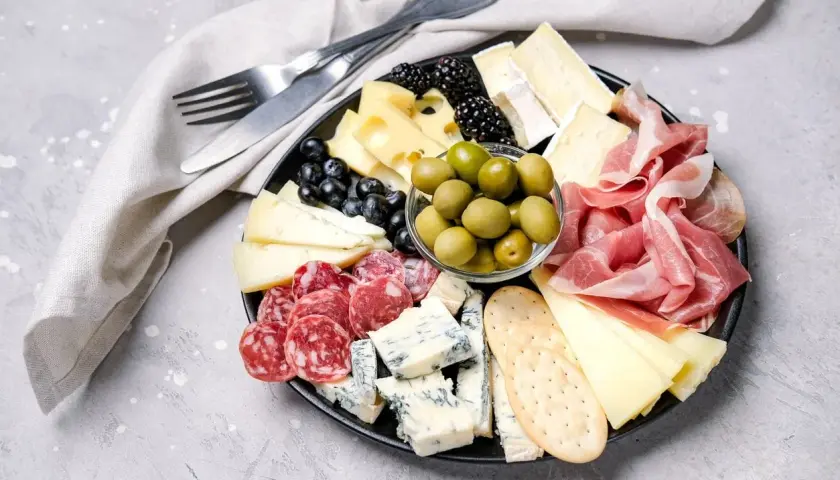 Bei taglieri con salumi, formaggi misti, olive verdi, frutti di bosco e cracker.