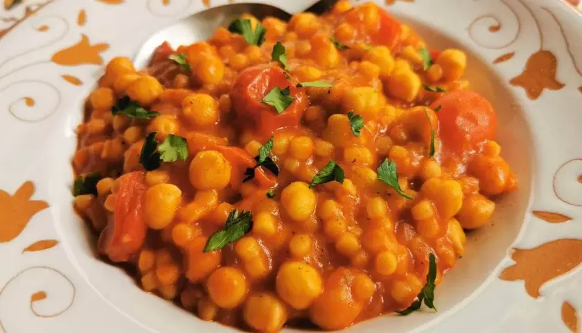 Piatto di ceci e pomodoro, guarnito con prezzemolo. Un sapore che ricorda la peretta formaggio, un classico.