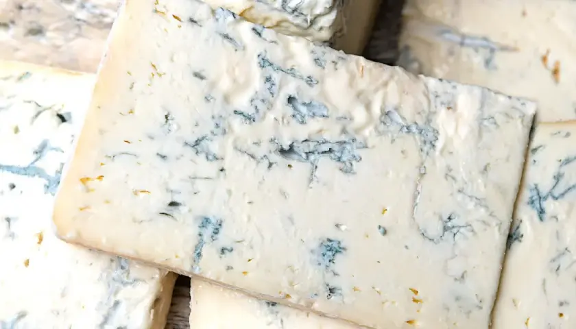 Fette di formaggio verde, con venature blu intenso, che ricordano il sapore deciso del gorgonzola.