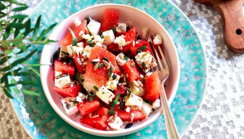 Insalata anguria e feta, fresca e colorata, con semi di girasole e zucca, guarnita con erbe aromatiche. Perfetta per l'estate.