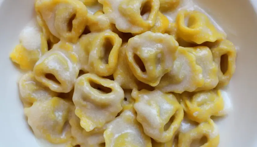 Tortellini freschi immersi in una cremosa fonduta di parmigiano, un abbraccio di sapore.